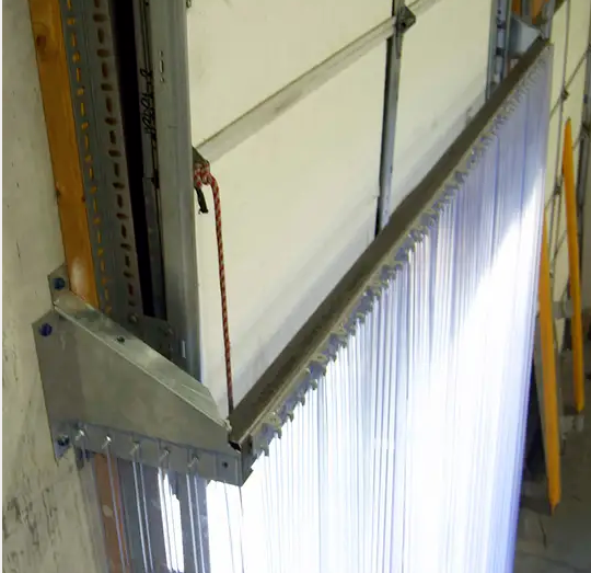 Stand-off bracket holding a strip curtain clear of a roll-up door track